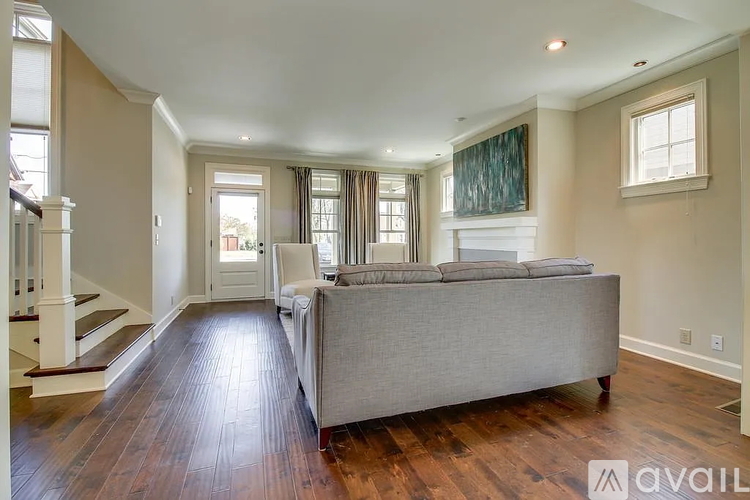 A living room with a grey couch and wooden floors.