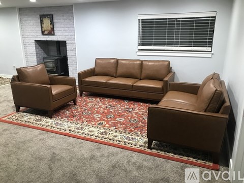 A living room with a fireplace and brown leather furniture.