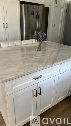 A kitchen with white cabinets and a marble countertop.