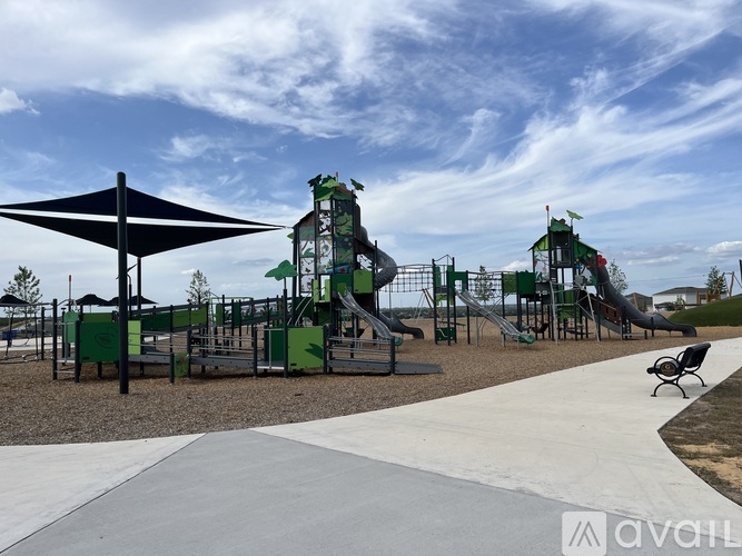 A playground with a green slide and a black umbrella.