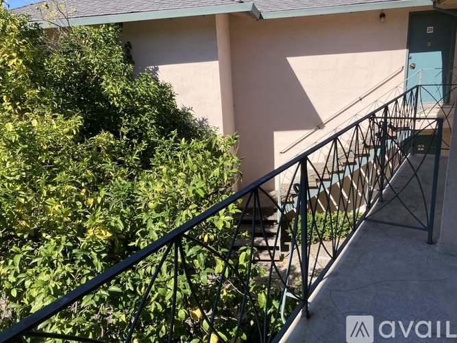 A house with a green bush in front and a metal railing.