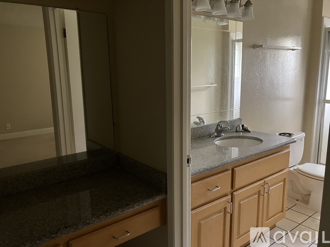 A bathroom with a sink, toilet, and mirror.