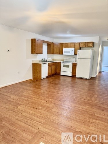 A kitchen with wooden floors and white appliances.