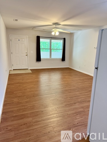 A room with wooden flooring and a window with black curtains.