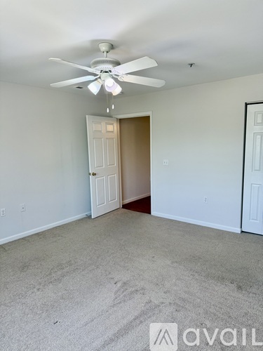 A room with a ceiling fan and carpeted floor.
