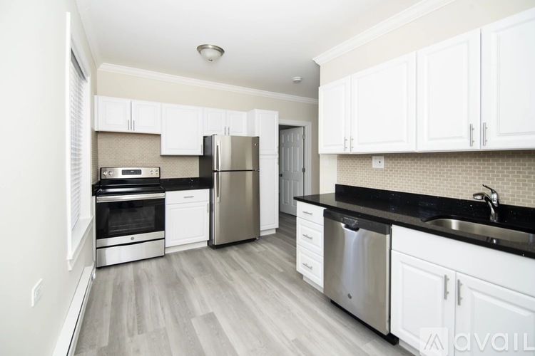 A kitchen with white cabinets and a black countertop.