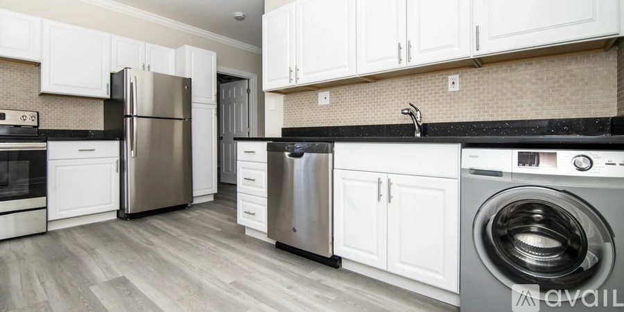 A modern kitchen with a stainless steel refrigerator and washing machine.