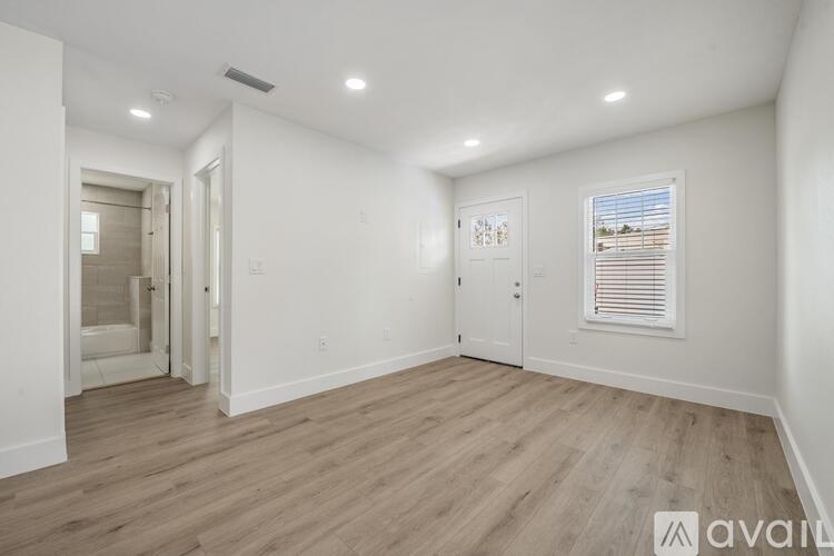 A spacious room with wooden flooring and white walls.