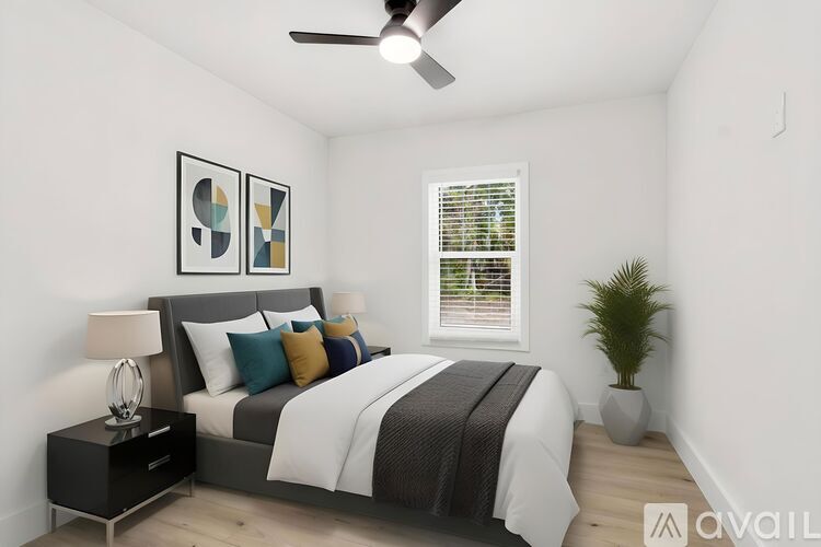 A bedroom with a bed, a ceiling fan, and a plant.