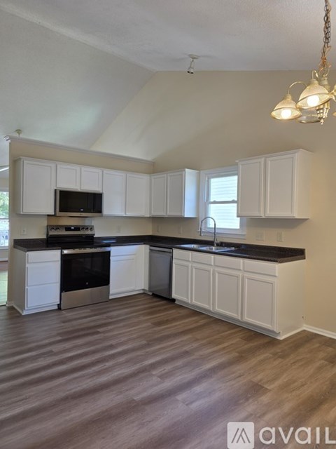 A kitchen with white cabinets and a black countertop.