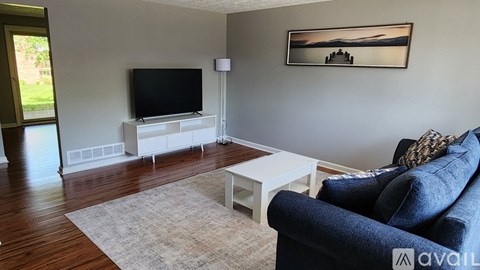 A living room with a blue couch and a television on a stand.