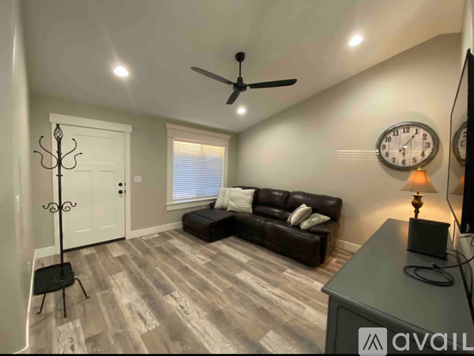 A living room with a brown couch and a fan on the ceiling.