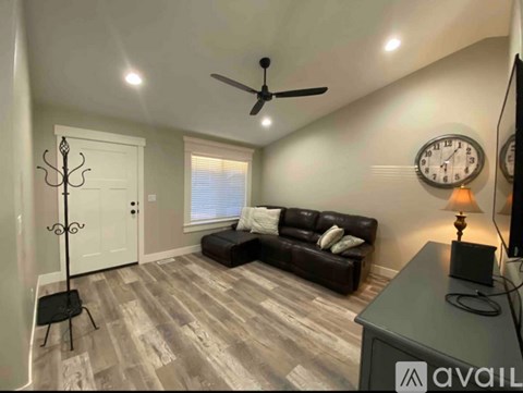 A living room with a brown couch and a fan on the ceiling.