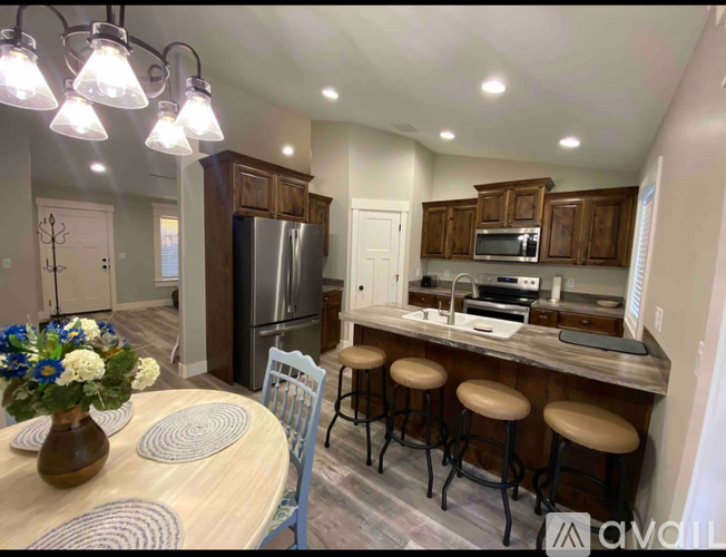 A kitchen with a table and chairs in front of a refrigerator.