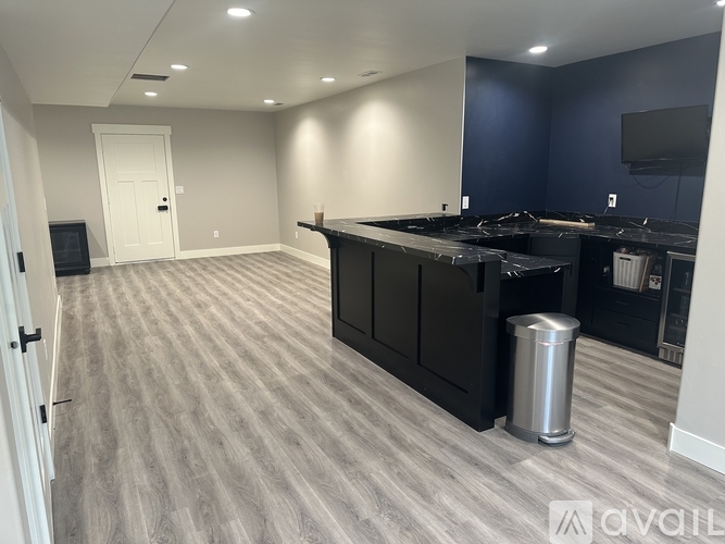 A spacious room with a grey carpet and a black countertop.