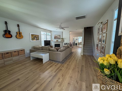 A living room with a wooden floor and a staircase in the background.