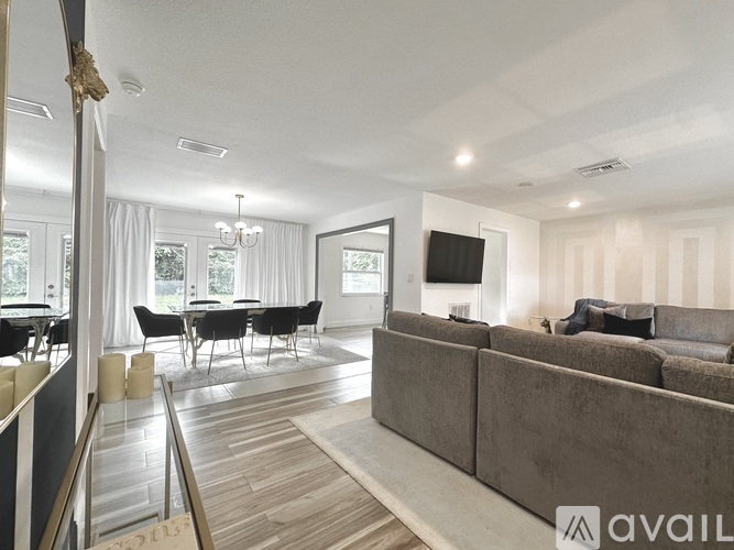 A living room with a grey couch and a dining table with chairs.