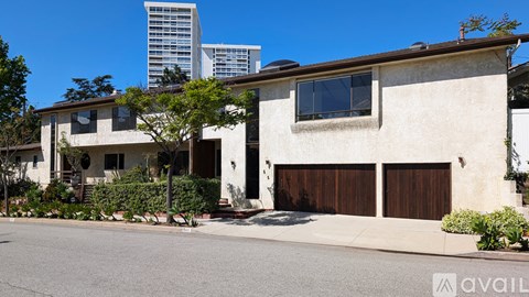 A two-story house with a garage and a tree in front.
