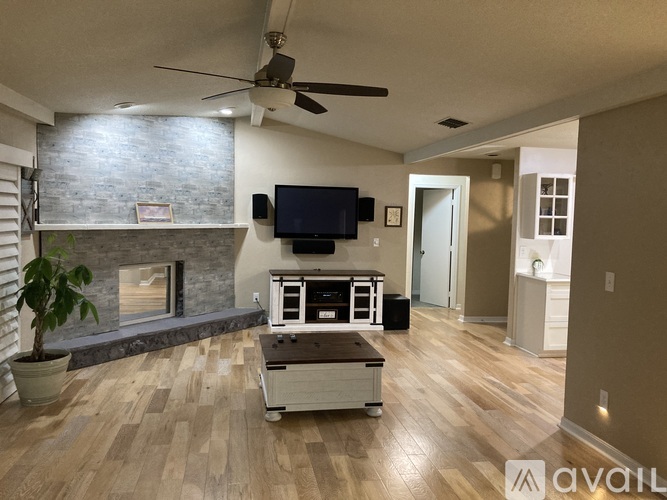 A living room with a fireplace and a television mounted above it.