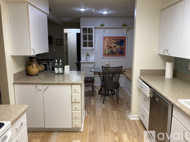 A kitchen with white cabinets and a wooden floor.