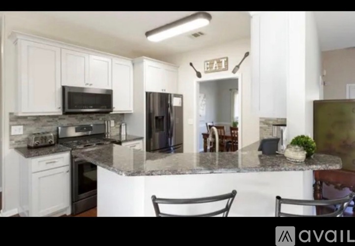 A kitchen with white cabinets and a granite countertop.