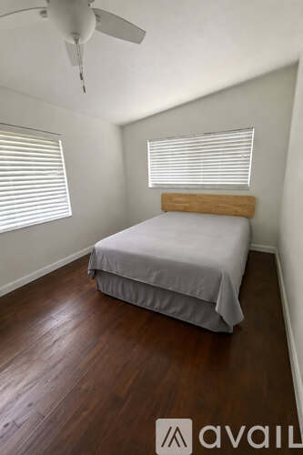 A bedroom with a bed, wooden headboard, and a ceiling fan.