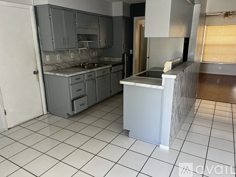 A kitchen with a white tile floor and grey cabinets.