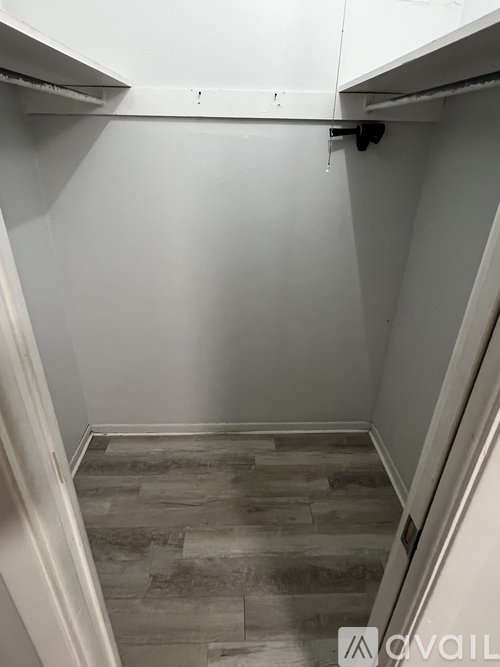 A hallway with a white wall and a wooden floor.