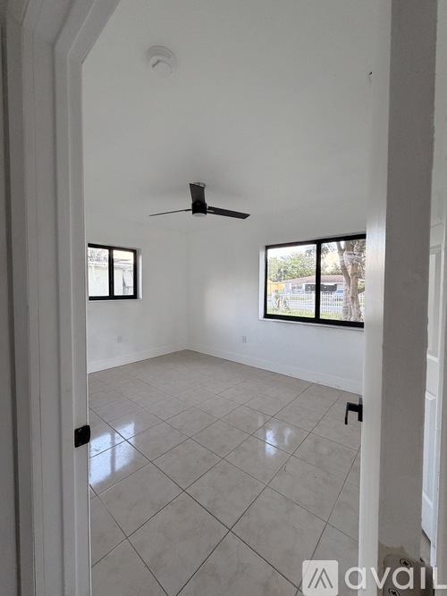 A room with a ceiling fan and two windows.