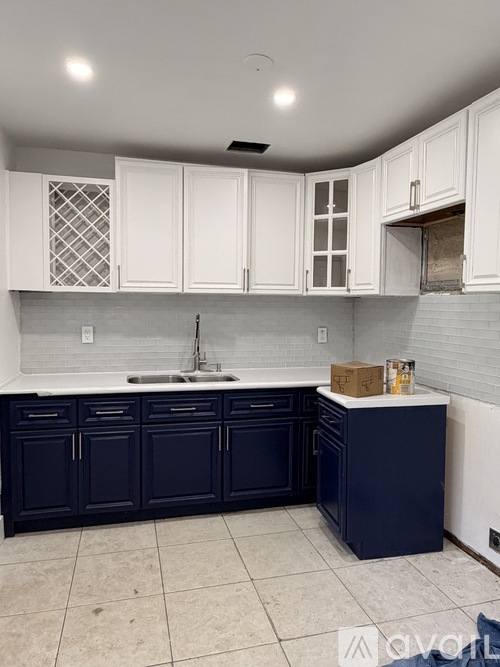 A kitchen with white cabinets and dark blue countertops.