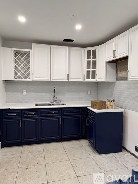 A kitchen with white cabinets and dark blue countertops.