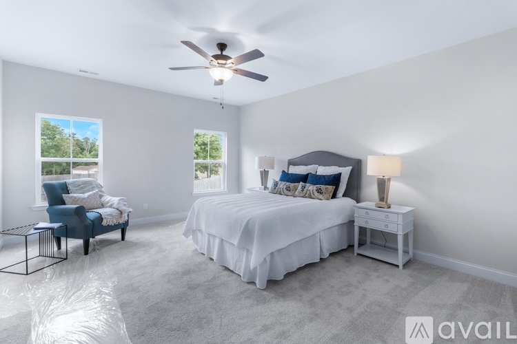 A bedroom with a bed, chair, and ceiling fan.