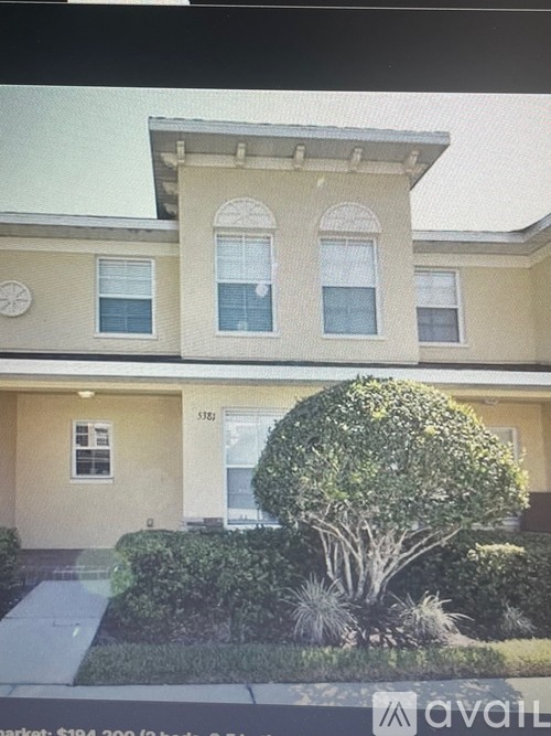 A two-story house with a large front yard and a tree.