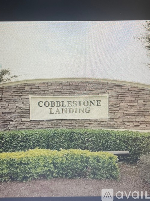 A sign that says Cobblestone Landing is mounted on a stone wall.