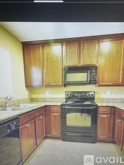 A kitchen with wooden cabinets and black appliances.