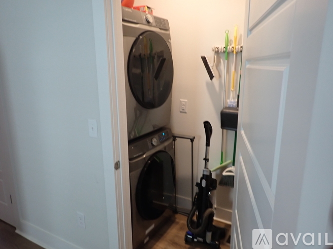 A black vacuum cleaner is on the floor next to a washing machine.