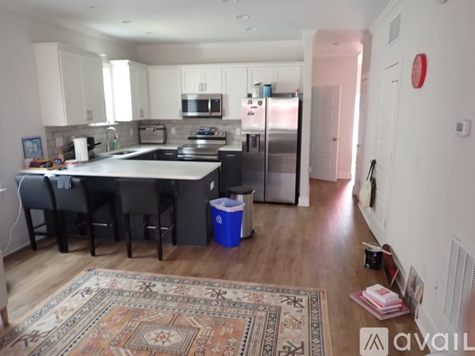A kitchen with a rug on the floor and a fridge to the right.