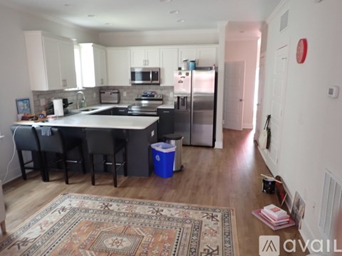 A kitchen with a rug on the floor and a fridge to the right.