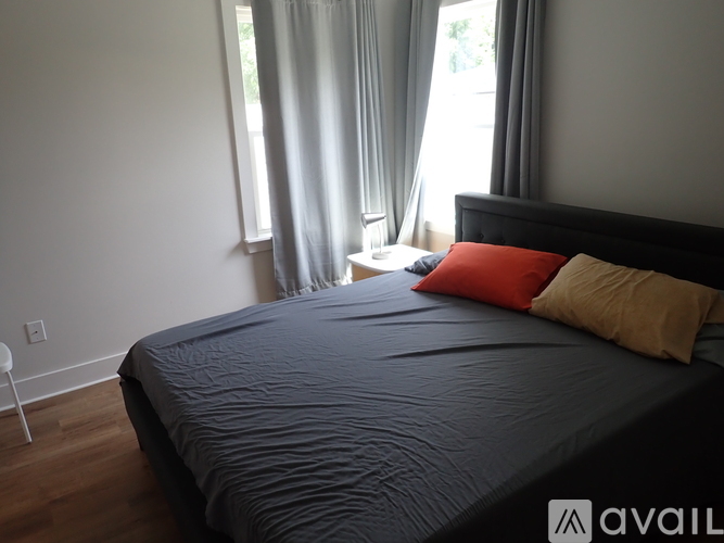 A bed with a grey comforter and a red pillow is in the image.
