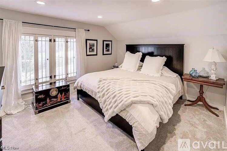 A bedroom with a large bed and a window with curtains.