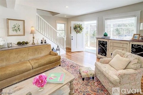 A living room with a tan couch, a coffee table with a pink flower, and a chest of drawers.