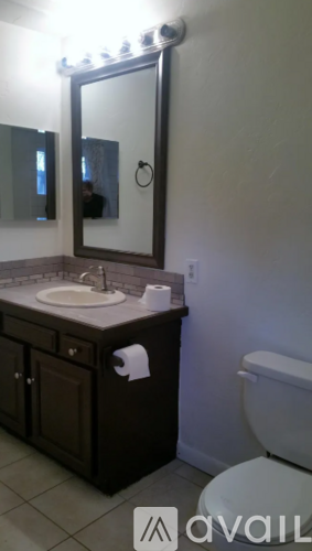A bathroom with a sink, mirror, toilet and cabinet.