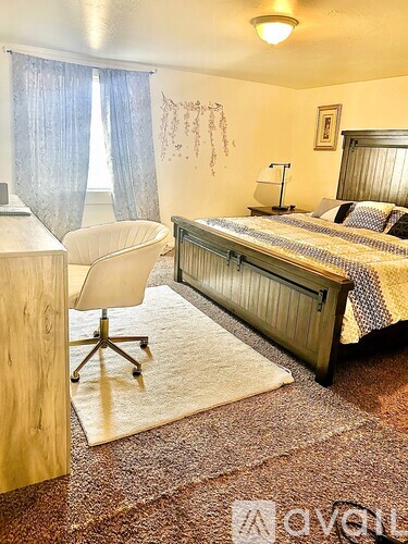 A bedroom with a bed, chair, and window.