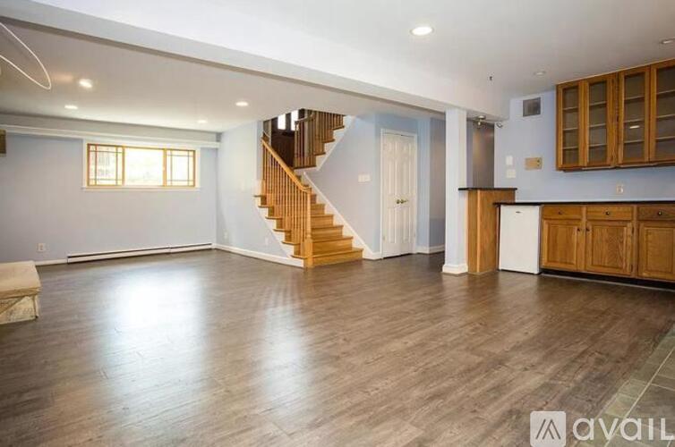 A spacious room with wooden flooring and a staircase.