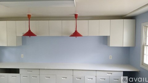 A kitchen with white cabinets and red hanging lamps.