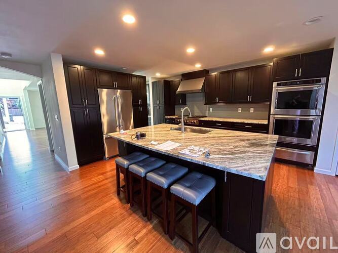 A kitchen with dark wood cabinets and a marble countertop.