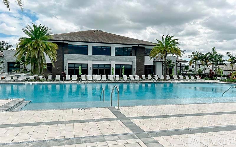 A large swimming pool in front of a building with a poolside lounge.