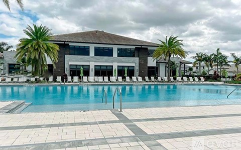 A large swimming pool in front of a building with a poolside lounge.