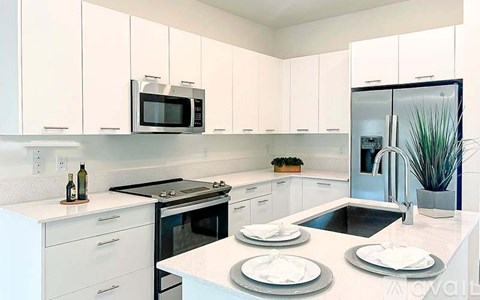 A modern kitchen with white cabinets and a stainless steel refrigerator.