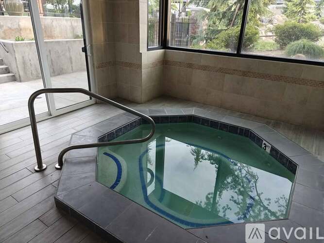 A hot tub sits on a tiled floor in a room with a glass door.